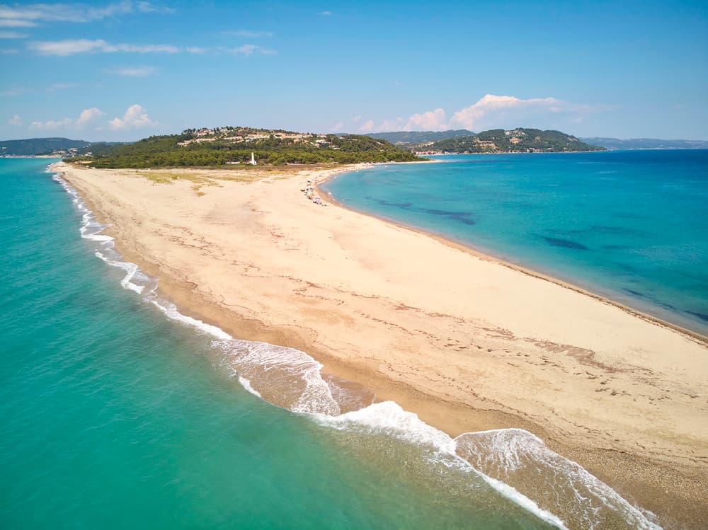 The long spit of sand extending into the sea at Possidi Cape, with the historic lighthouse in the background.