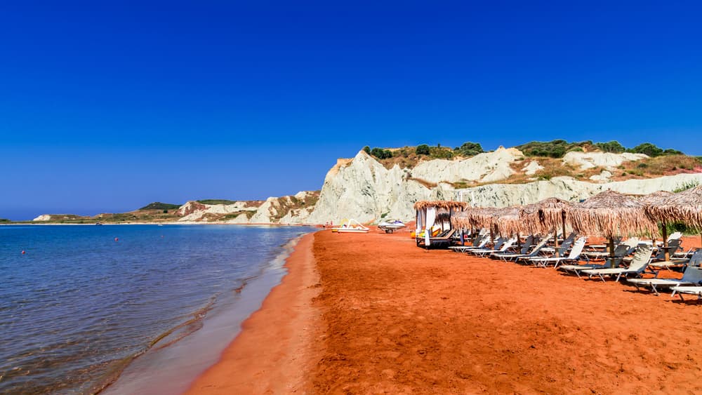 The unique reddish-orange sand and grey clay cliffs of Xi Beach, Kefalonia.