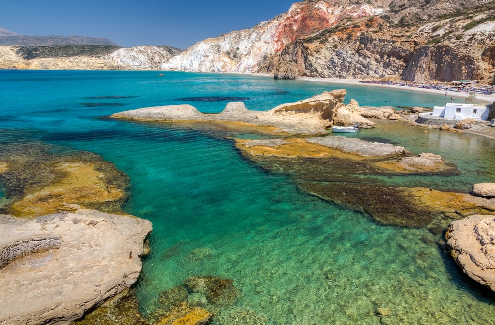 The long sandy shore and immense, colorful volcanic cliffs of Firiplaka Beach, Milos.