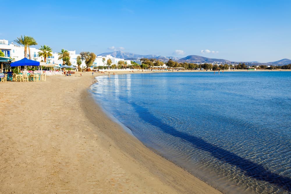 Sun umbrellas and calm, shallow waters at the family-friendly Agios Georgios Beach in Naxos Town.