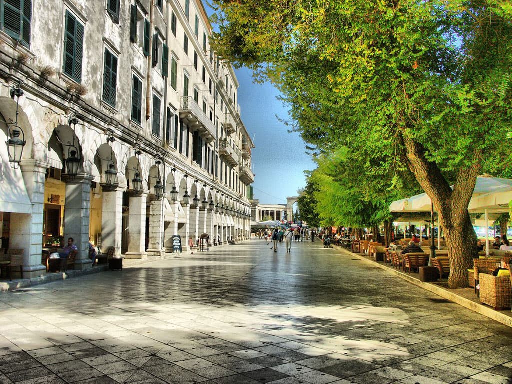 People enjoying coffee and drinks under the elegant archways of The Liston Promenade in Corfu Town.