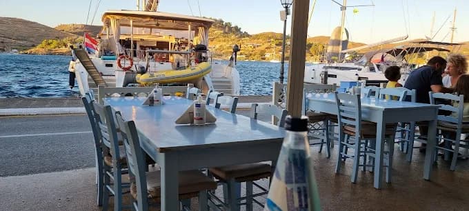 A plate of fresh lobster spaghetti at Aristos Taverna with yachts in the Vourkari marina background.