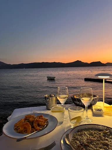 Romantic sunset dining with tables on the sand in front of the colorful 'syrmata' houses of Klima.