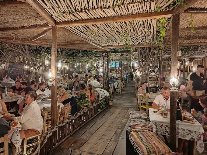The charming and rustic garden setting of O! Hamos! Tavern in Milos, with handwritten menus.
