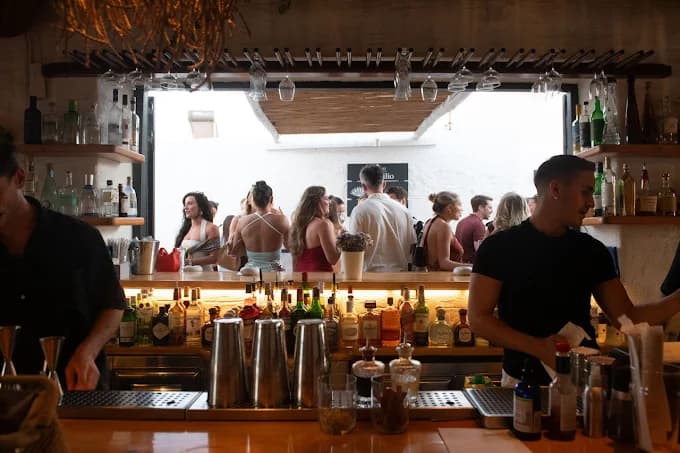 The lively atmosphere on the balcony of Agosta Bar, overlooking the old port of Naoussa at night.